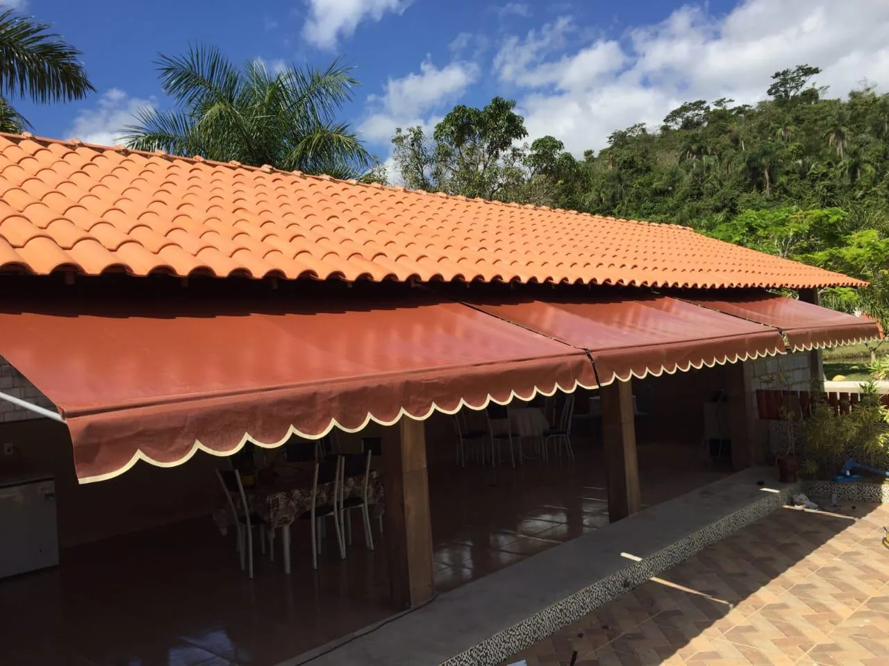Toldo retrátil com braços laranja aberto ao longo da varanda de uma casa