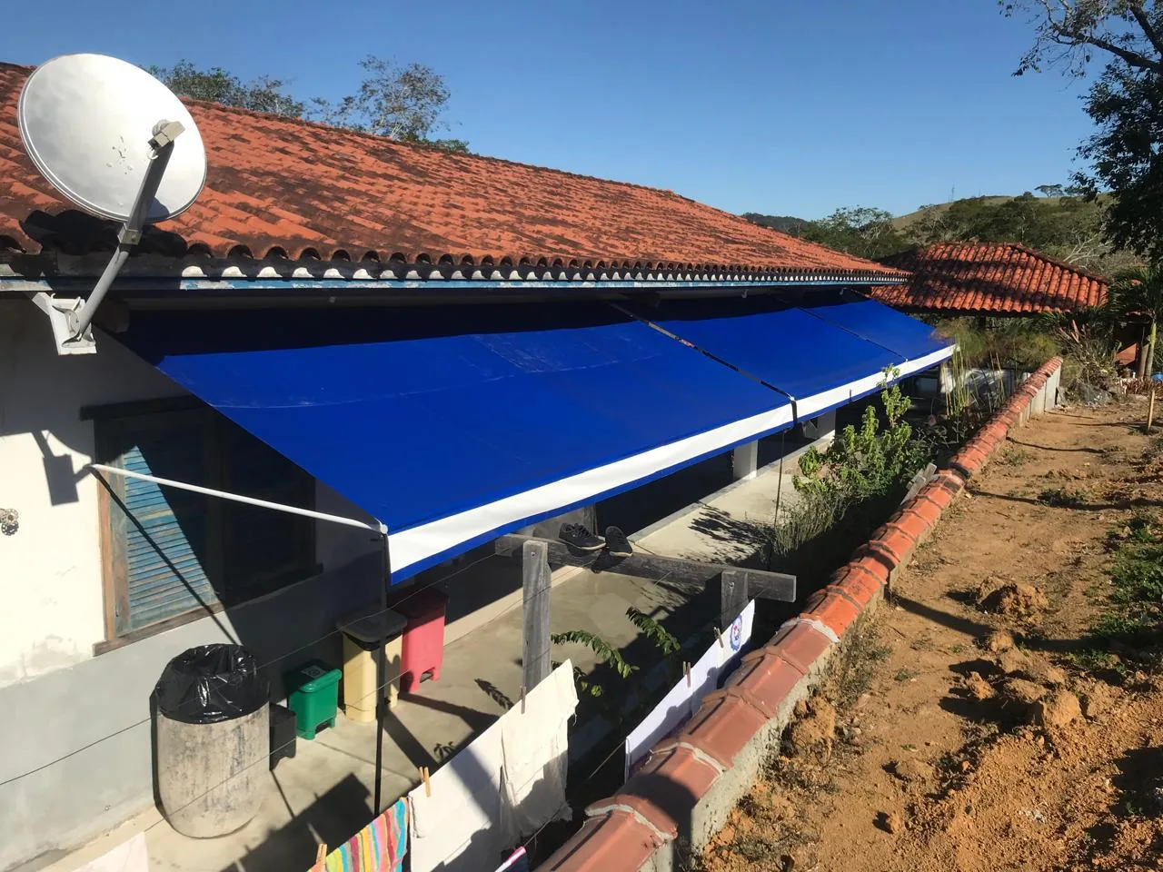 Toldo retrátil com braços azul avançando sobre a área externa de uma residência