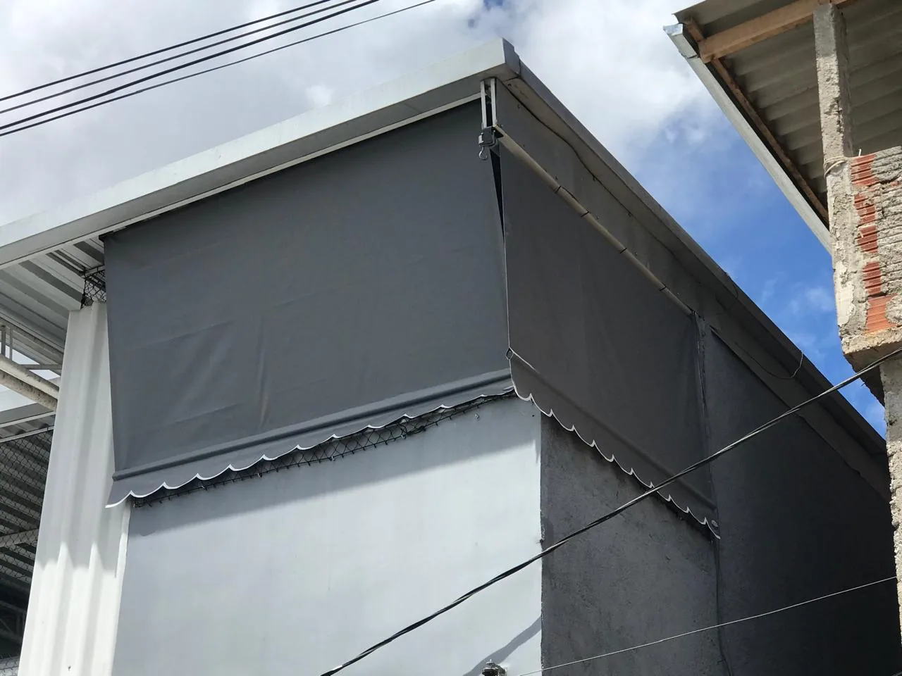 Toldo cortina cinza descido protegendo janela de sol e chuva
